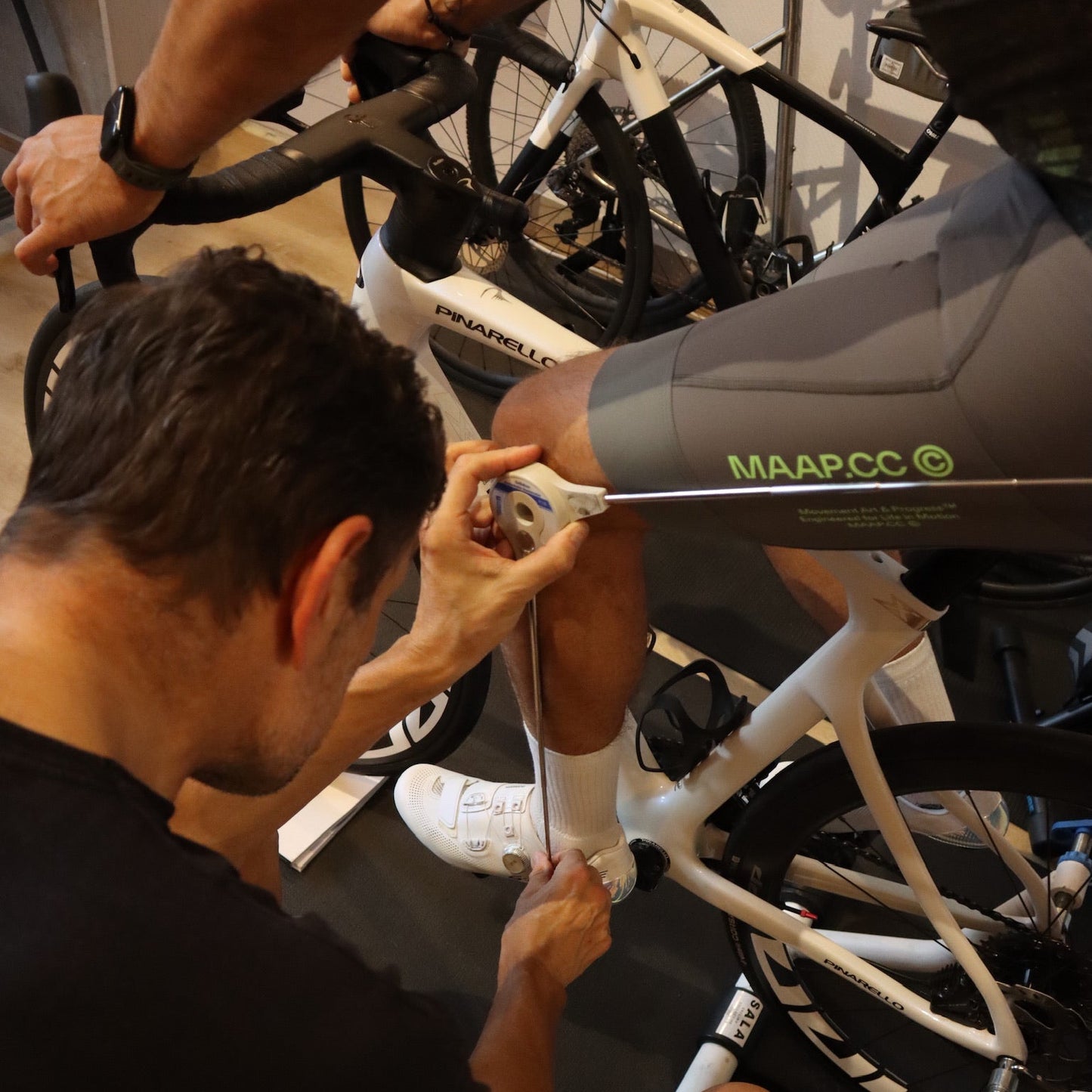 Person working on a bicycle with another person in the background