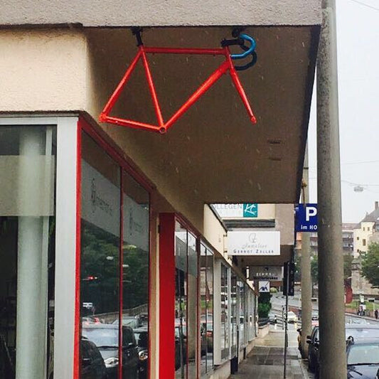 Red bicycle sculpture hanging from a building overhang
